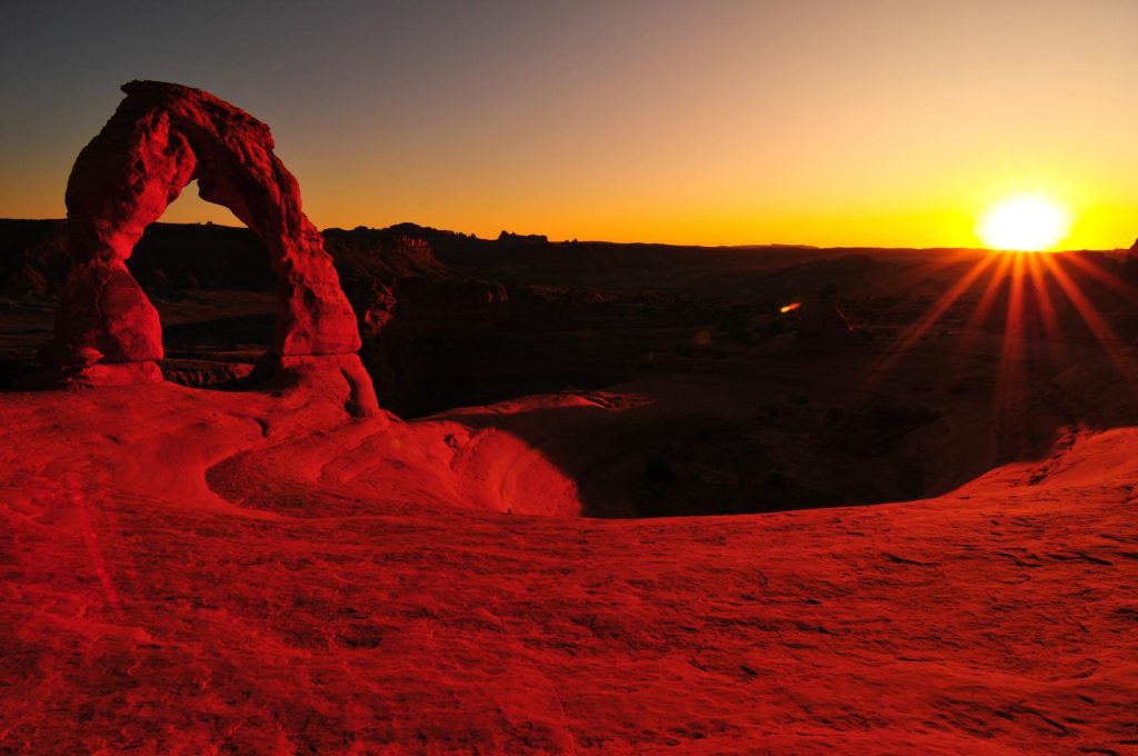 Sun setting on the horizon at Delicate Arch, Arches National Park